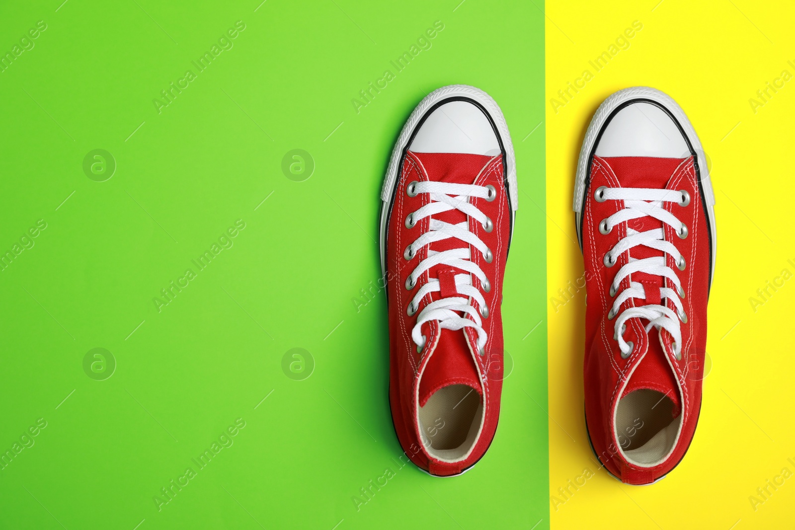 Photo of Pair of new stylish red sneakers on colorful background, flat lay. Space for text