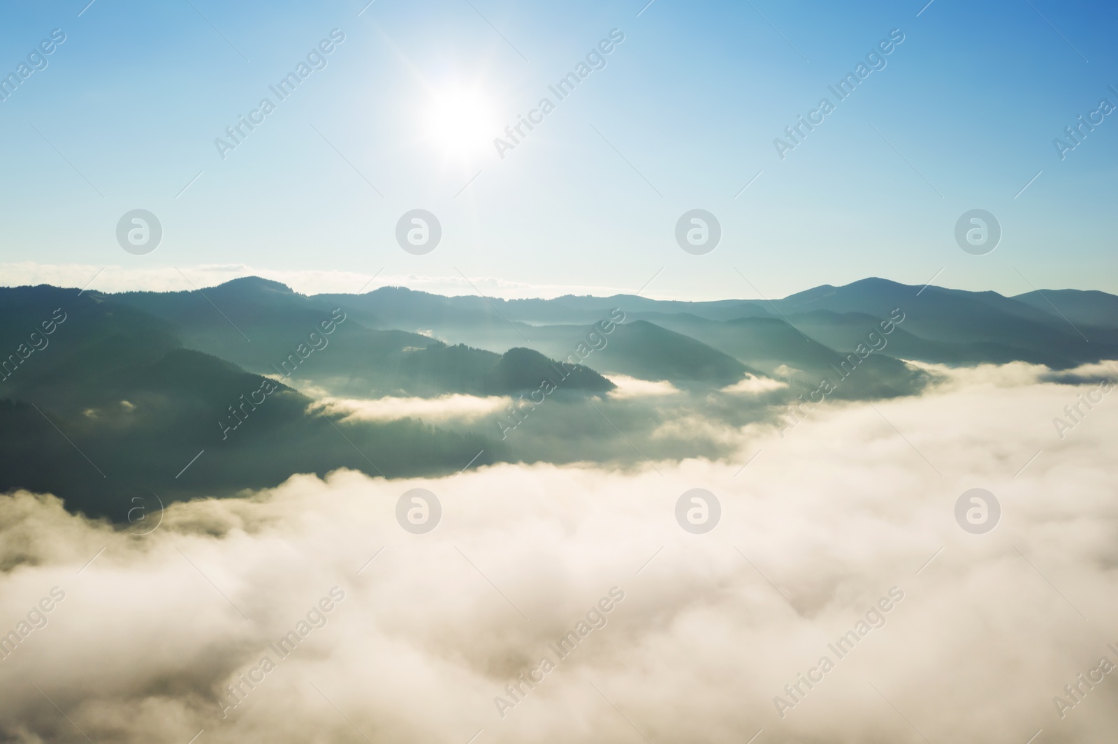 Image of Aerial view of beautiful mountains covered with fluffy clouds on sunny day. Drone photography