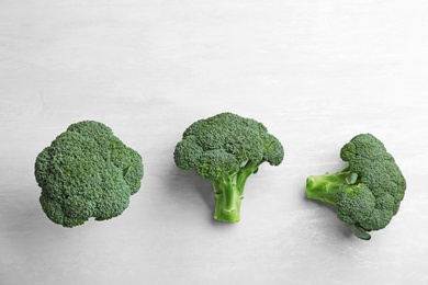 Photo of Fresh broccoli florets on light grey table, flat lay
