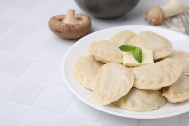 Photo of Delicious dumplings (varenyky) with tasty filling and butter on white table, closeup. Space for text