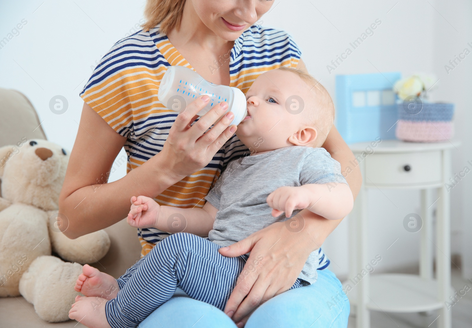 Photo of Lovely mother feeding her baby from bottle in room at home