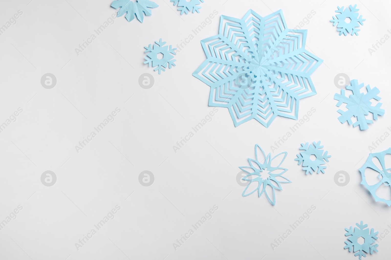 Photo of Many paper snowflakes on white background, flat lay. Space for text