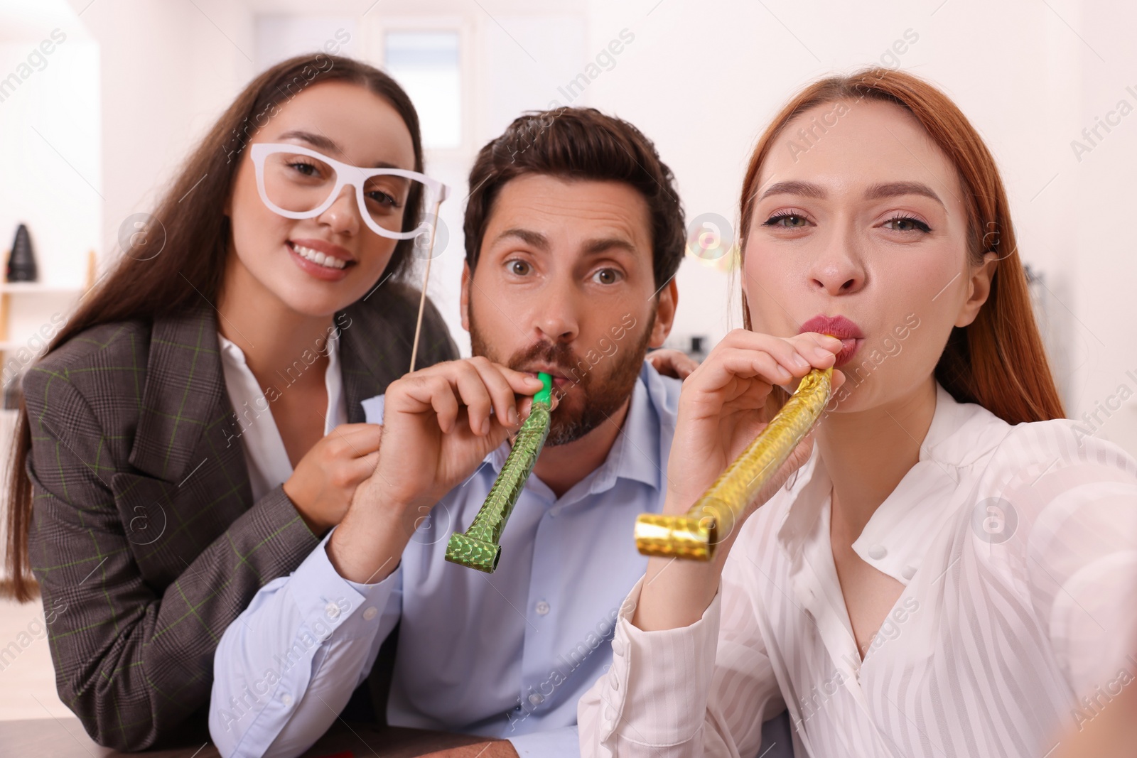 Photo of Coworkers taking selfie during office party indoors