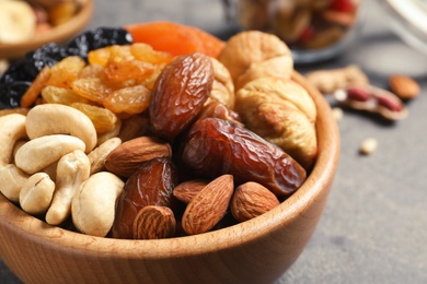Bowl with different dried fruits and nuts on table, closeup
