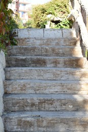 View of empty old staircase with wooden railing outdoors on sunny day