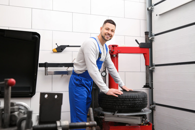 Mechanic working with tire fitting machine at car service