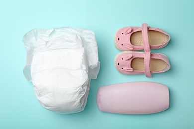 Diaper, child's shoes and bottle on light blue background, flat lay