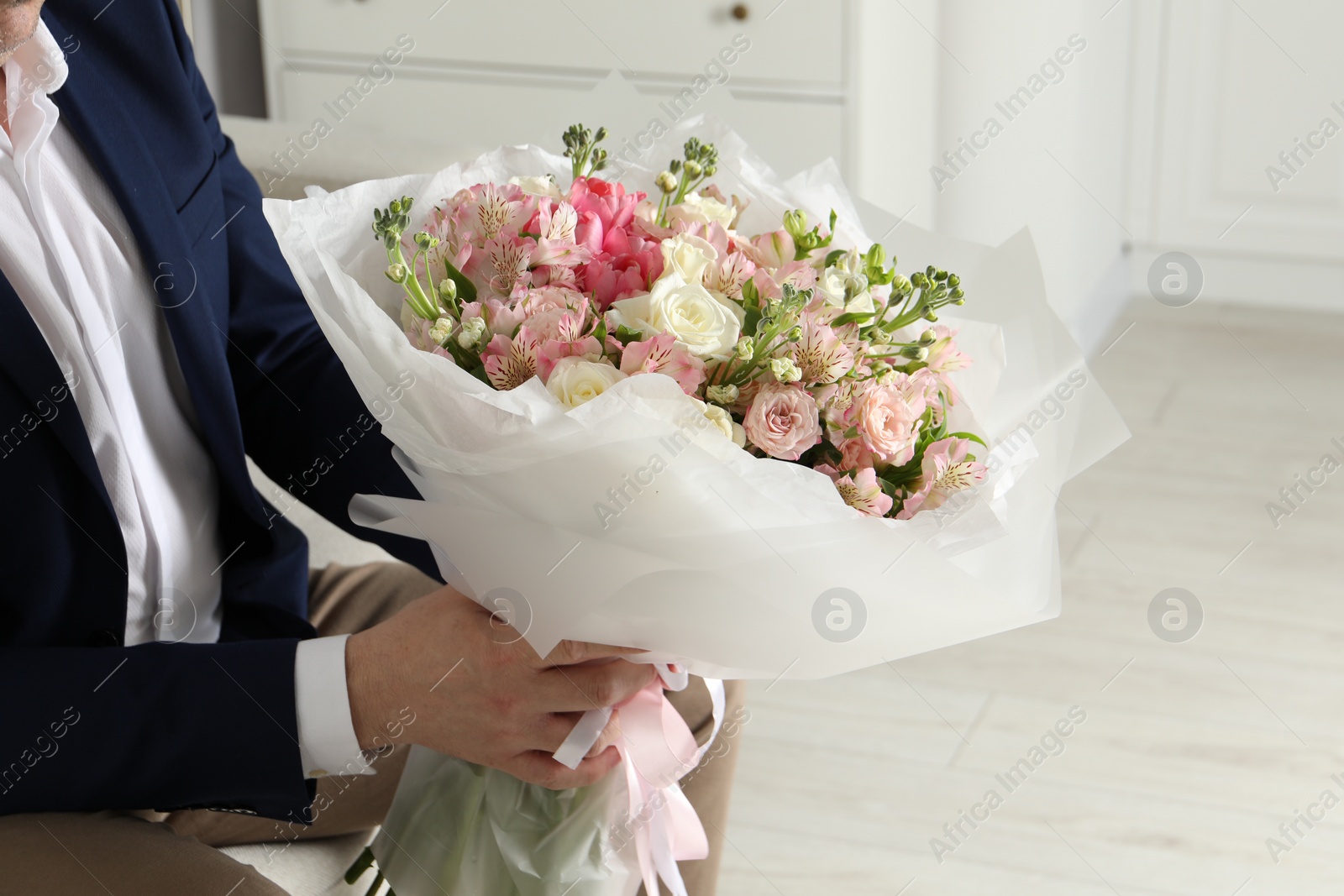 Photo of Man with beautiful bouquet of flowers indoors, closeup