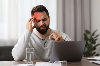Image of Man with pill suffering from headache at workplace indoors