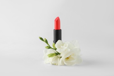 Photo of Beautiful lipstick and flowers on white background
