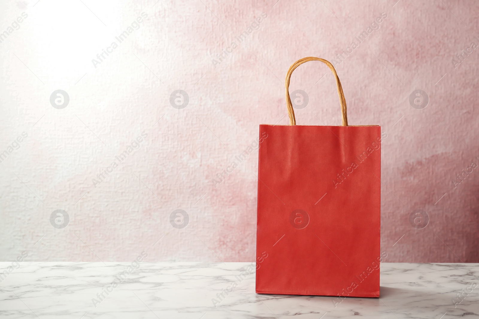 Photo of Mockup of paper shopping bag on table against color background