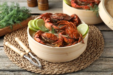 Photo of Delicious boiled crabs with lime and dill served on wooden table