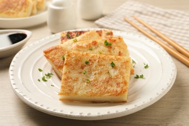 Photo of Delicious turnip cake with parsley served on wooden table, closeup