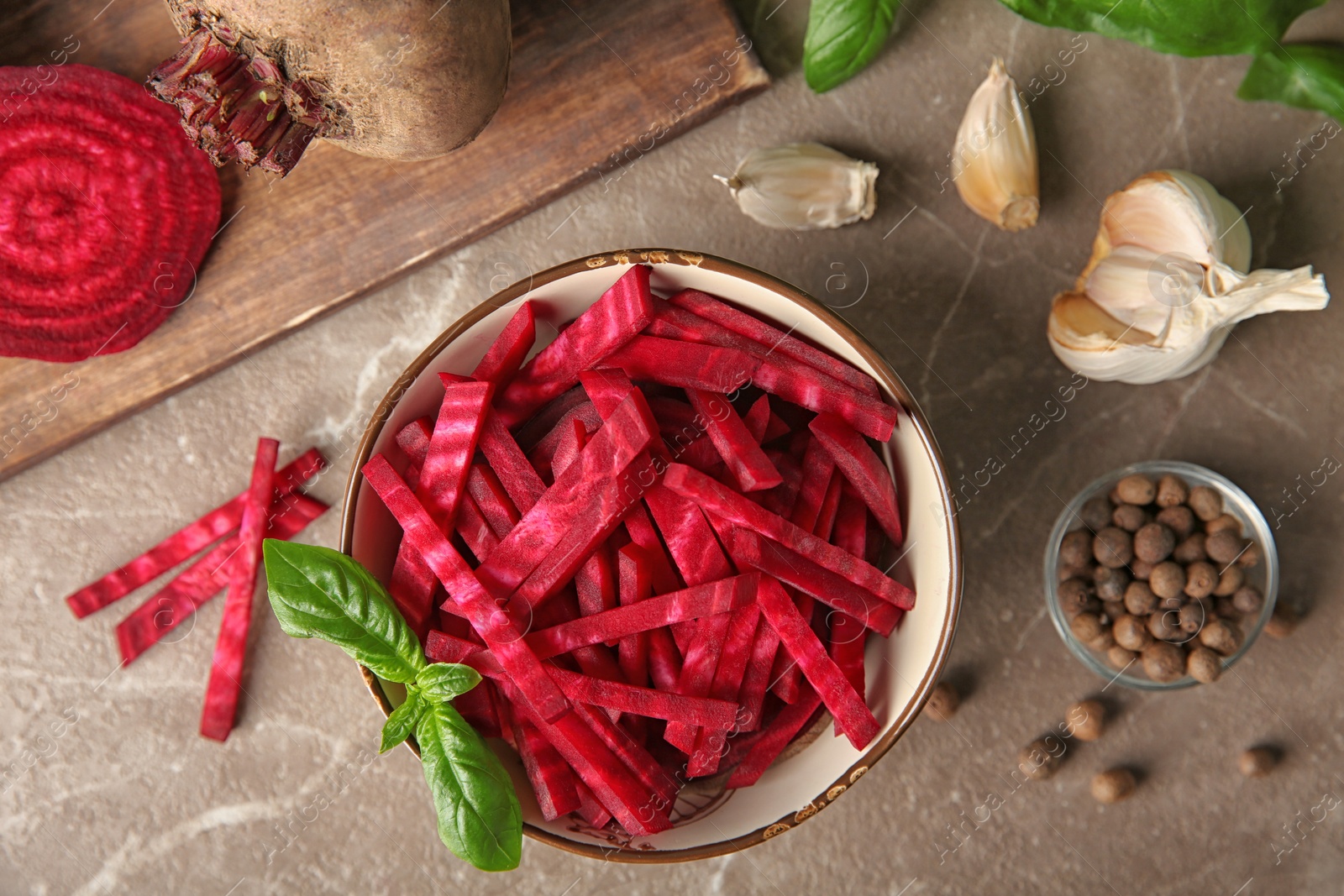 Photo of Bowl of cut fresh beets with basil, garlic and allspice on marble table, flat lay