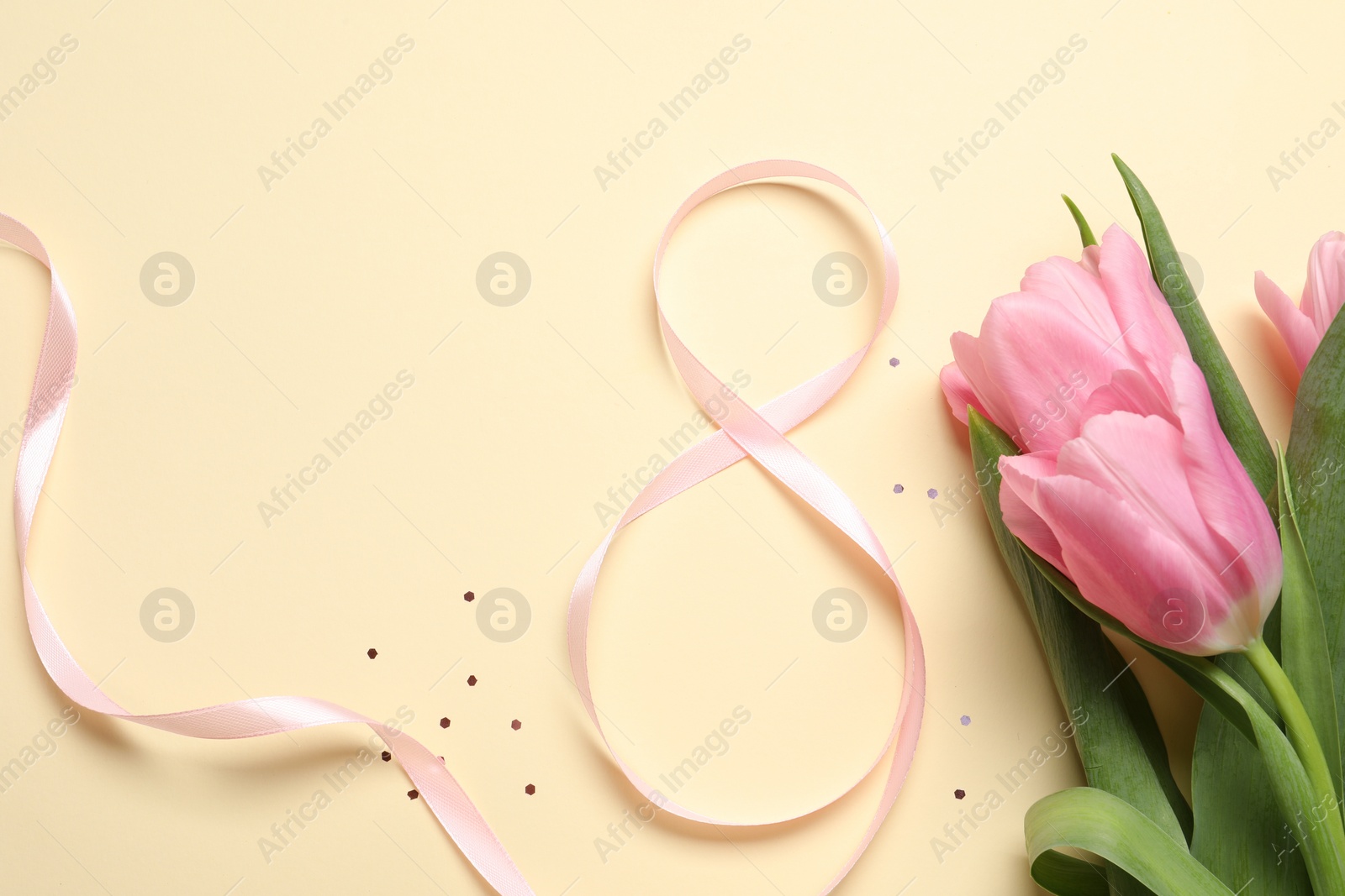 Photo of 8th of March greeting card design with pink ribbon, beautiful flowers and space for text on beige background, flat lay. International Women's day