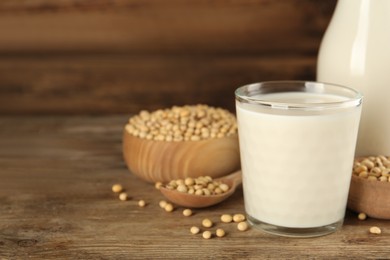 Photo of Glass with fresh soy milk and grains on wooden table. Space for text