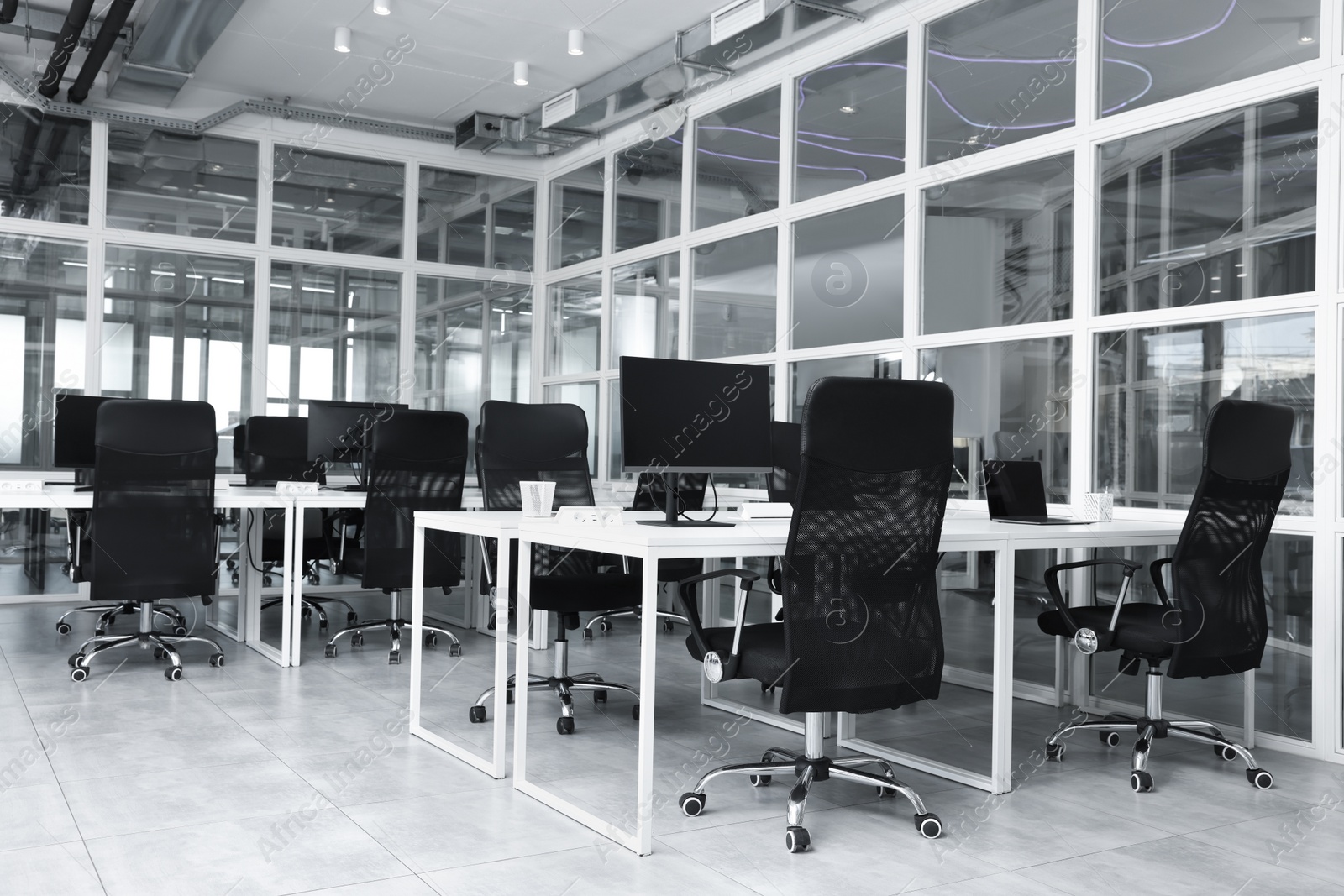 Photo of Stylish interior of open plan office. Workspace with computers, tables and chairs