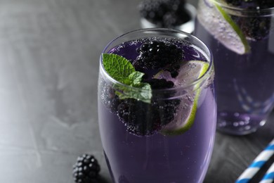 Photo of Delicious blackberry lemonade made with soda water on grey table, closeup