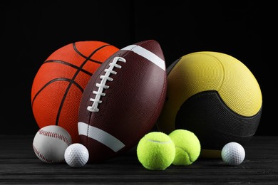 Photo of Many different sport balls on dark wooden table against black background
