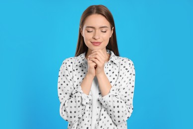 Photo of Woman with clasped hands praying on turquoise background