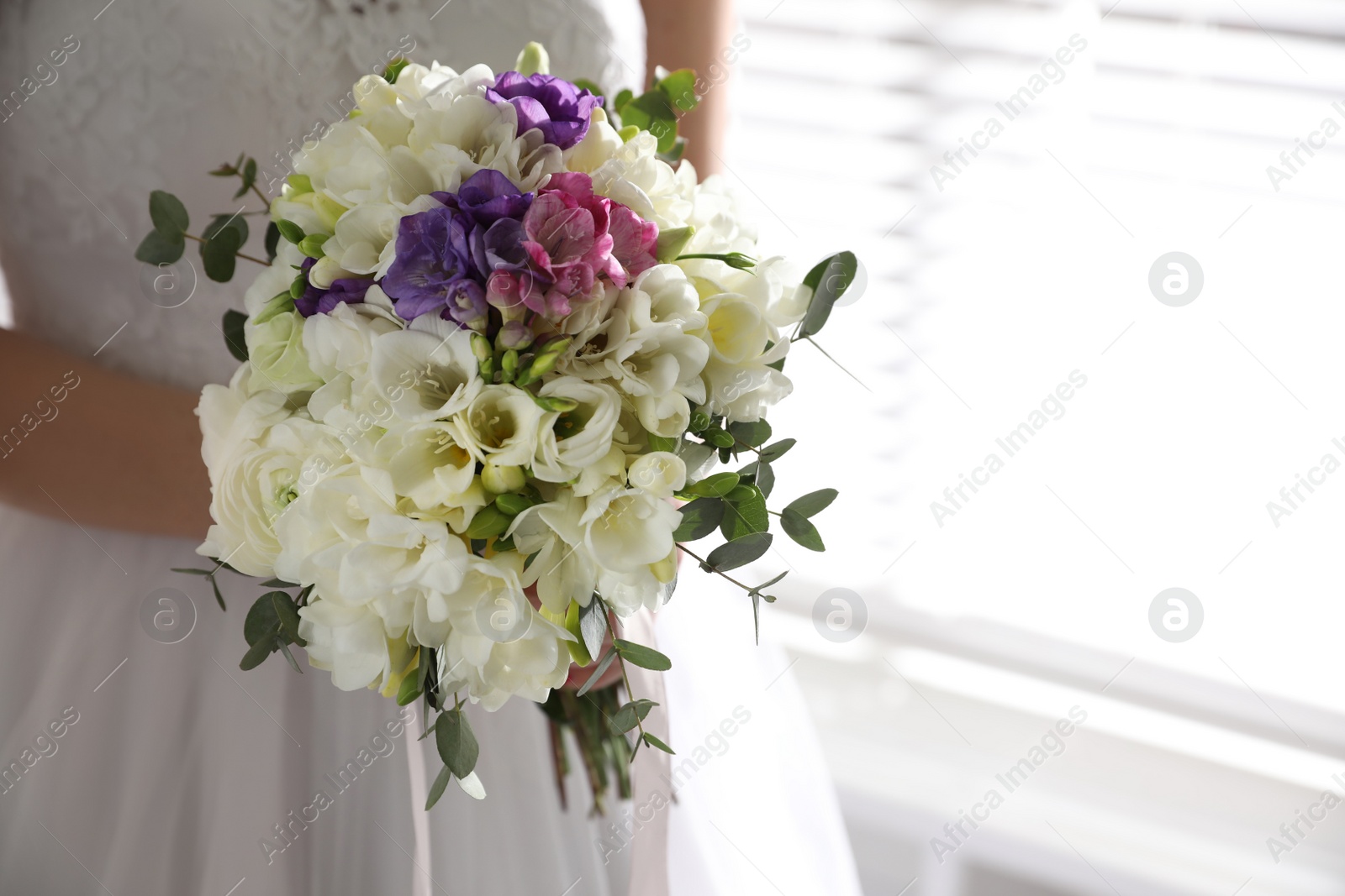 Photo of Bride holding beautiful bouquet with spring freesia flowers, closeup