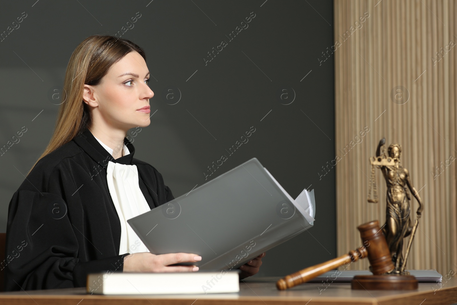 Photo of Judge with folder working at table in courtroom