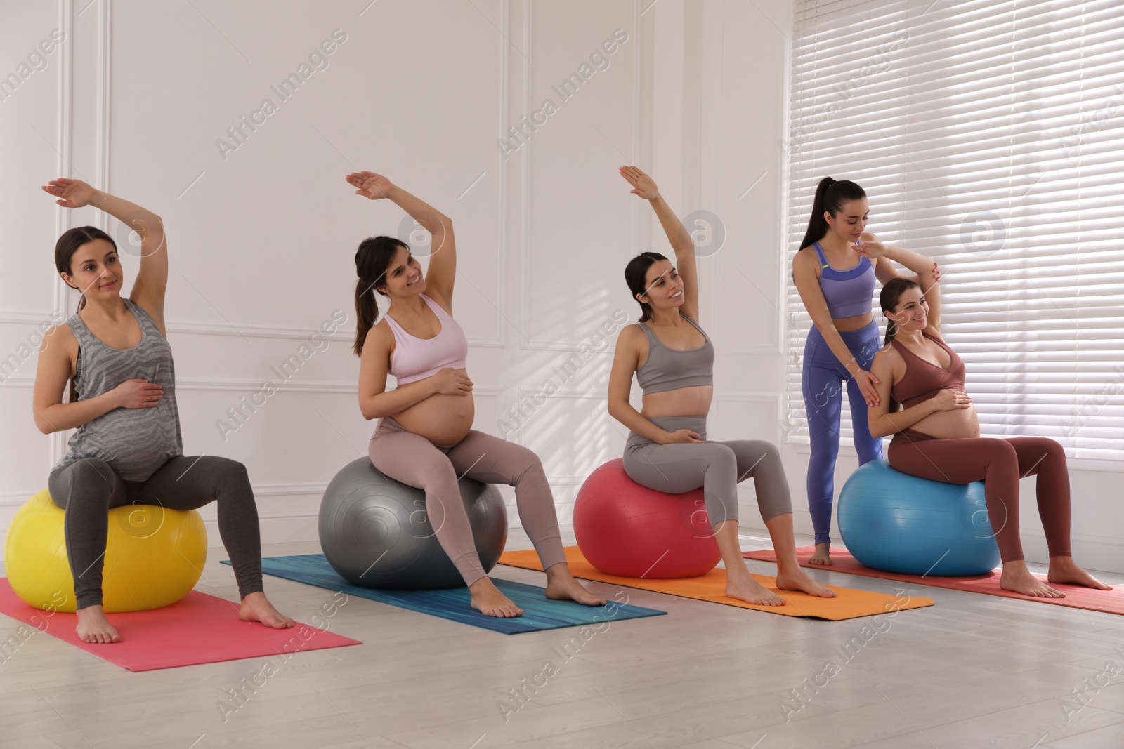 Photo of Trainer working with group of pregnant women in gym. Preparation for child birth