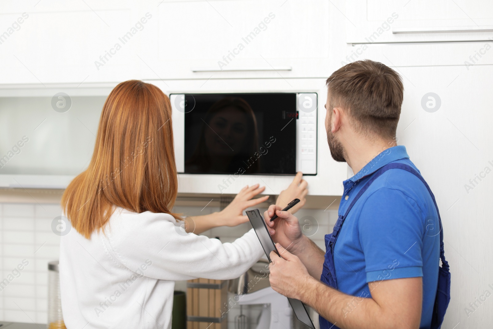 Photo of Housewife and repairman near microwave oven in kitchen