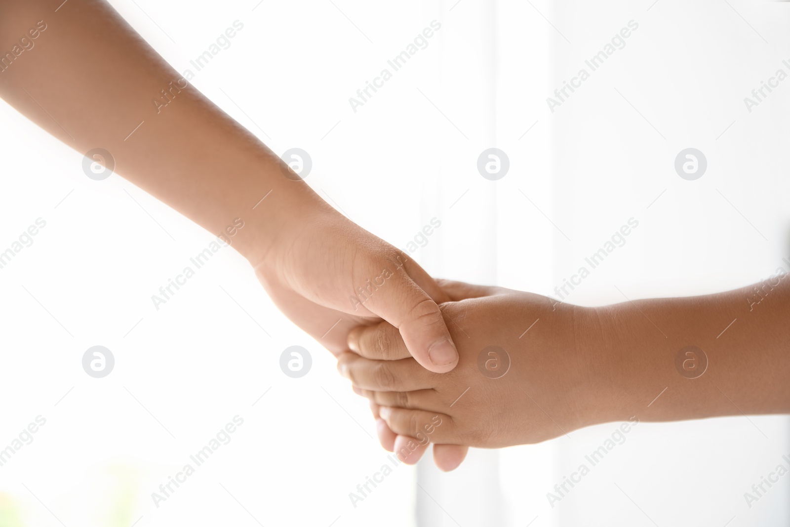 Photo of Children holding hands on light background, closeup. Unity concept
