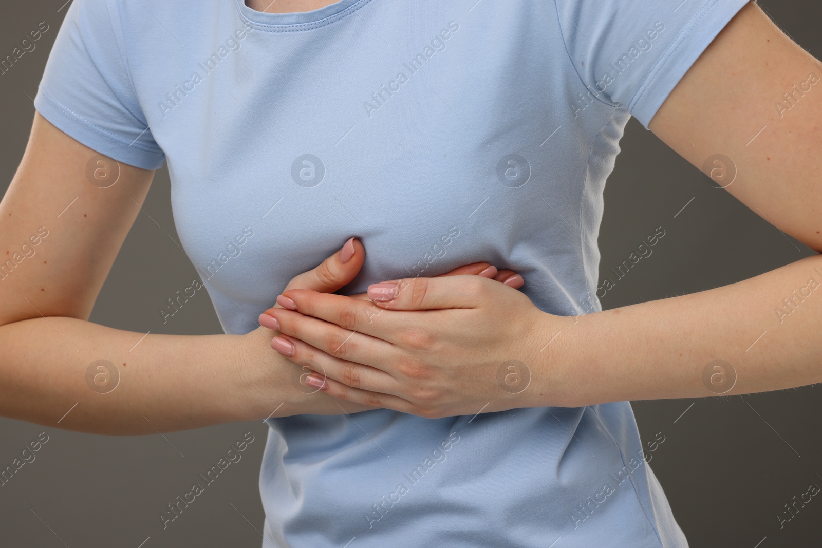 Photo of Woman having heart attack on grey background, closeup