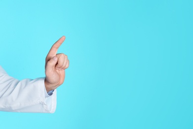 Photo of Male doctor pointing on color background, closeup with space for text