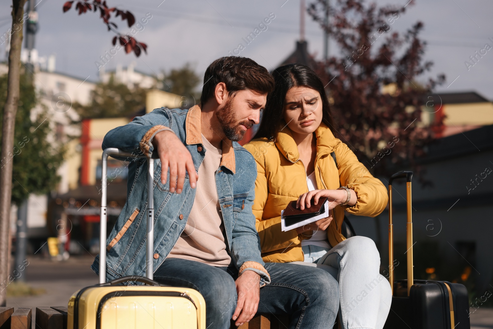 Photo of Being late. Worried couple with suitcases waiting outdoors
