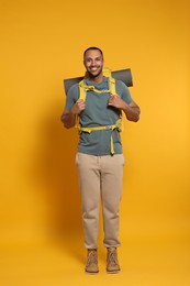 Photo of Happy tourist with backpack on yellow background