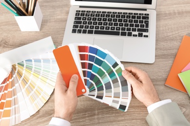 Photo of Male designer working with color palette at office table, closeup