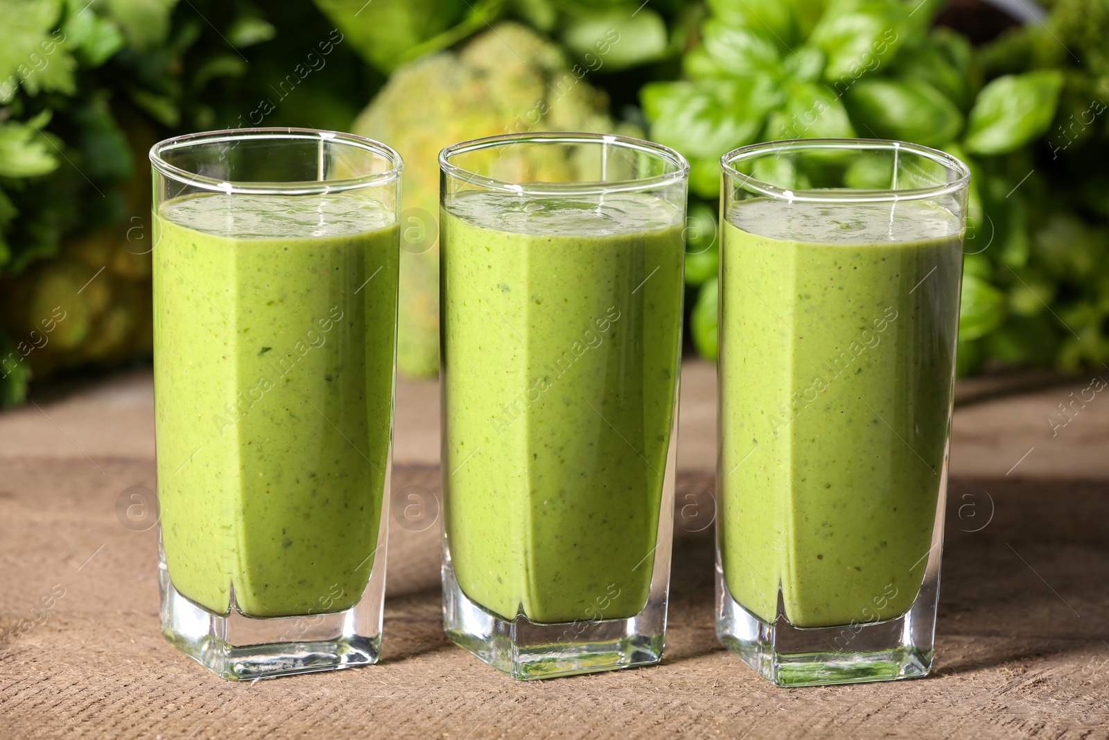 Photo of Glasses of fresh green smoothie and ingredients on wooden table