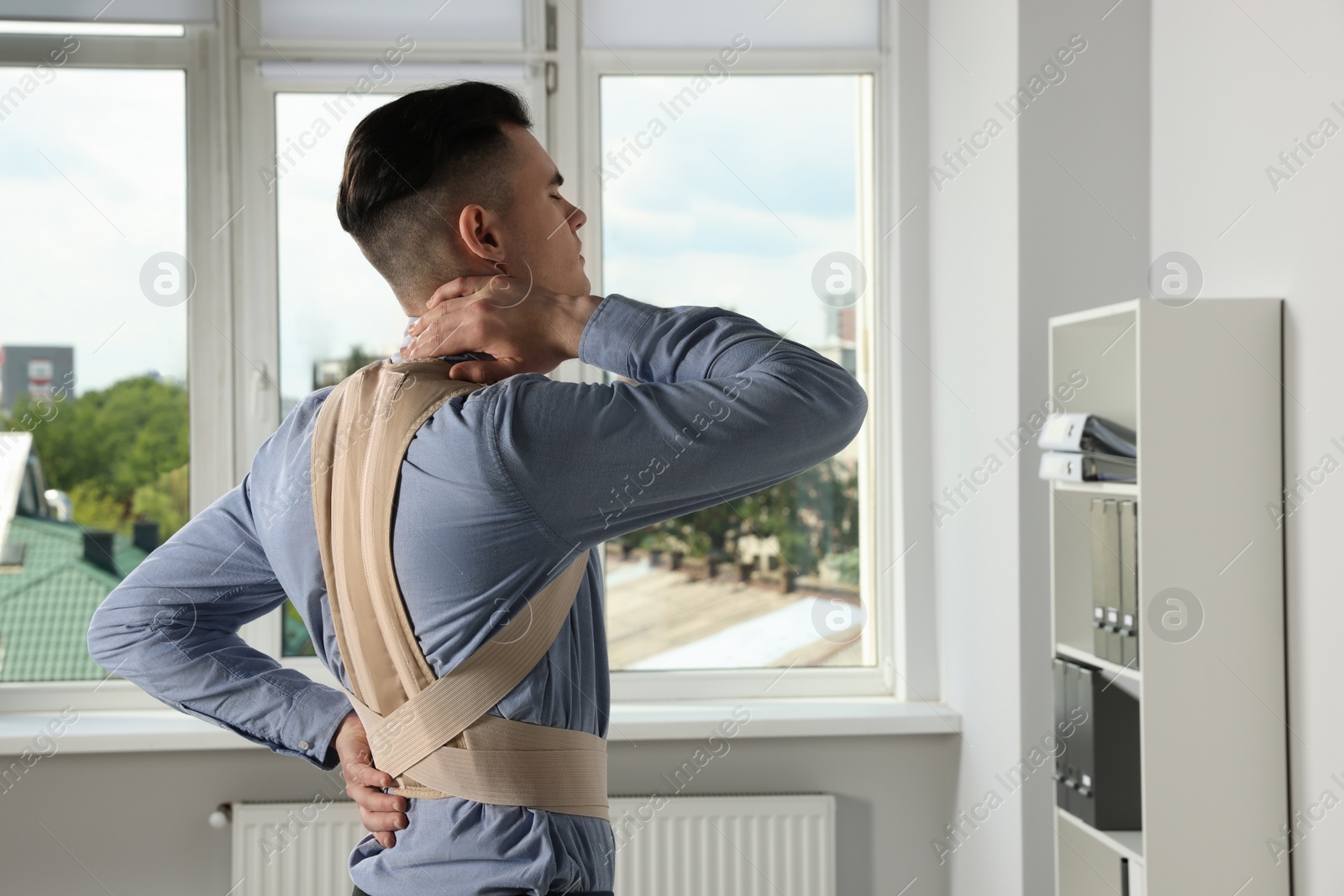 Photo of Young man with orthopedic corset in room