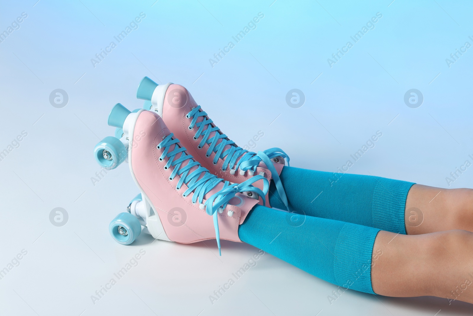 Photo of Woman with vintage roller skates on color background, closeup