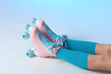 Photo of Woman with vintage roller skates on color background, closeup