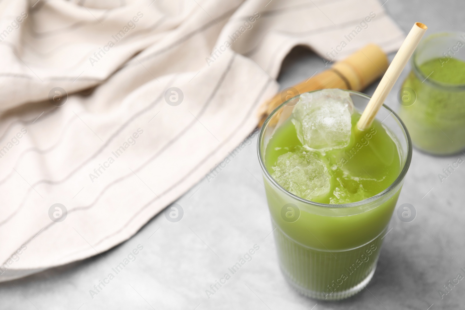 Photo of Glass of delicious iced green matcha tea on light grey table, above view. Space for text