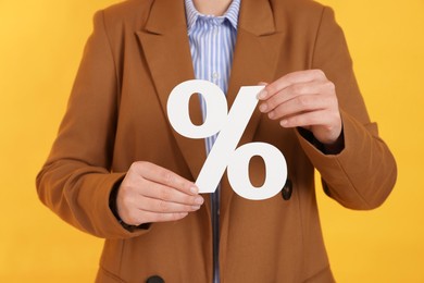 Woman holding percent sign on orange background, closeup