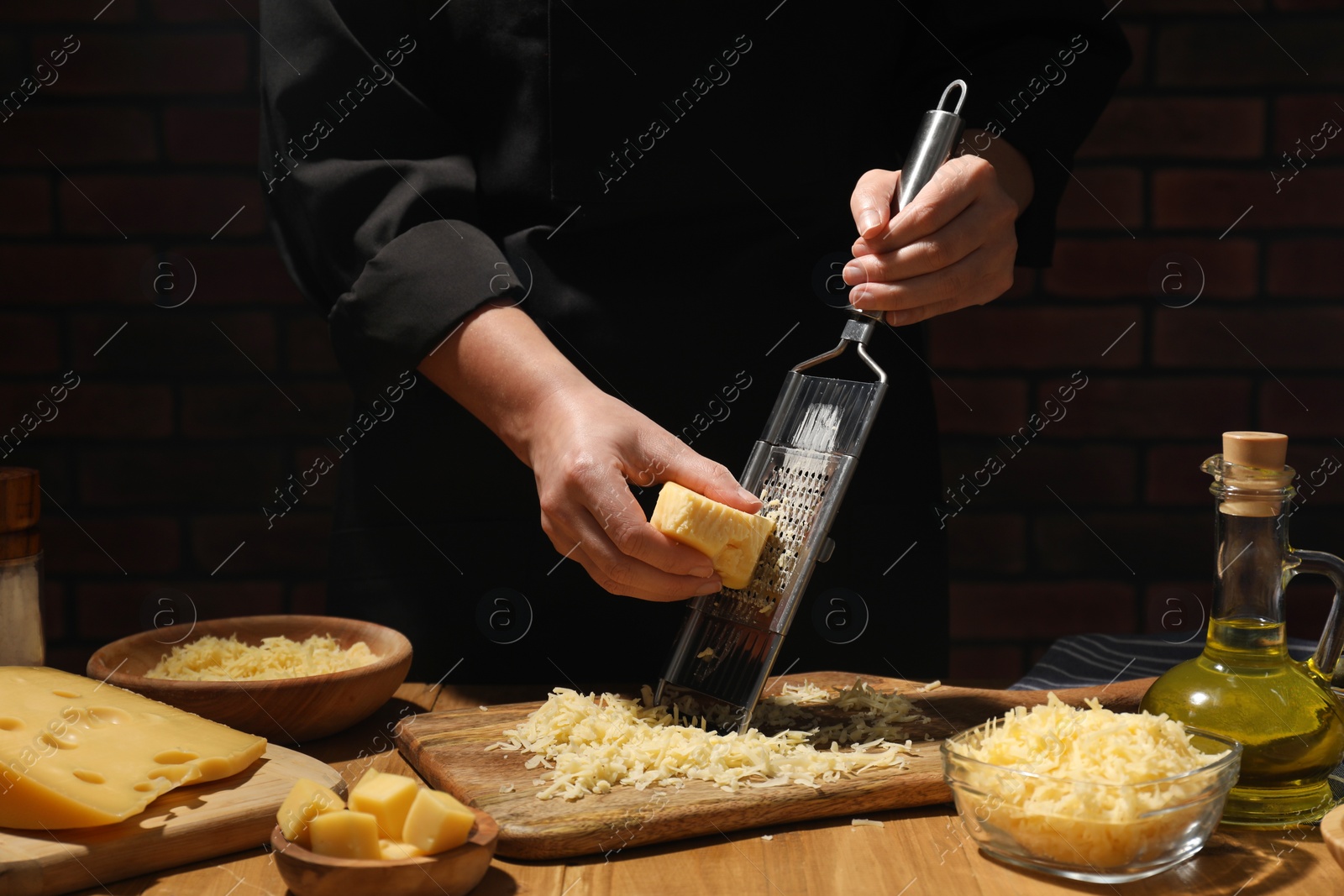 Photo of Woman grating cheese at wooden table, closeup