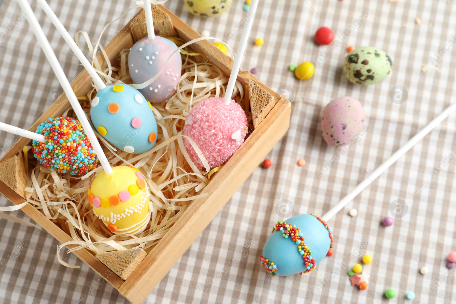Photo of Delicious sweet cake pops in wooden crate on table. Easter holiday