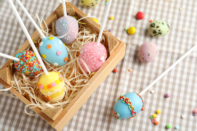 Photo of Delicious sweet cake pops in wooden crate on table. Easter holiday