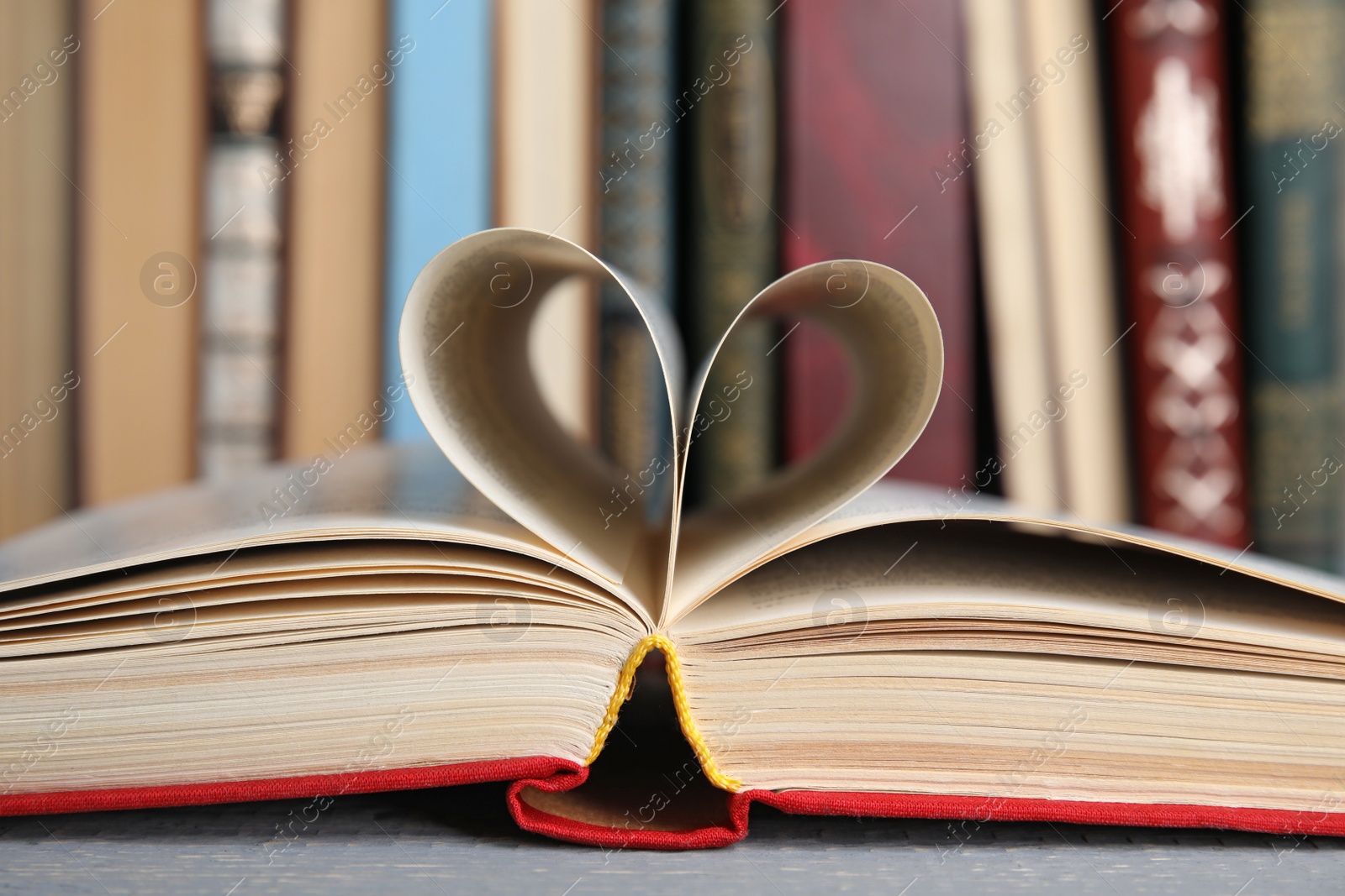 Photo of Open hardcover book on grey wooden table, closeup