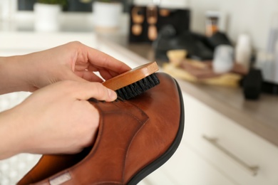 Photo of Woman cleaning stylish footwear indoors, closeup. Shoe care accessories