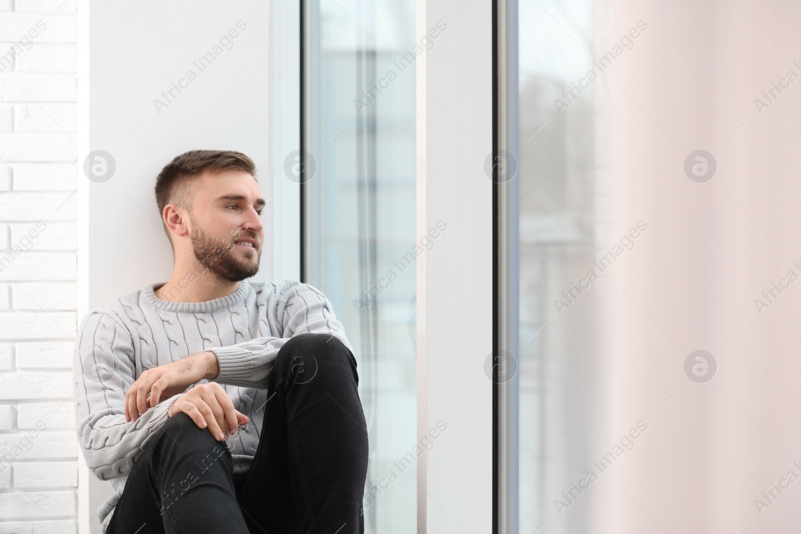 Photo of Handsome young man near window at home