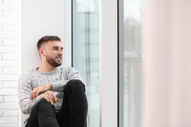 Handsome young man near window at home