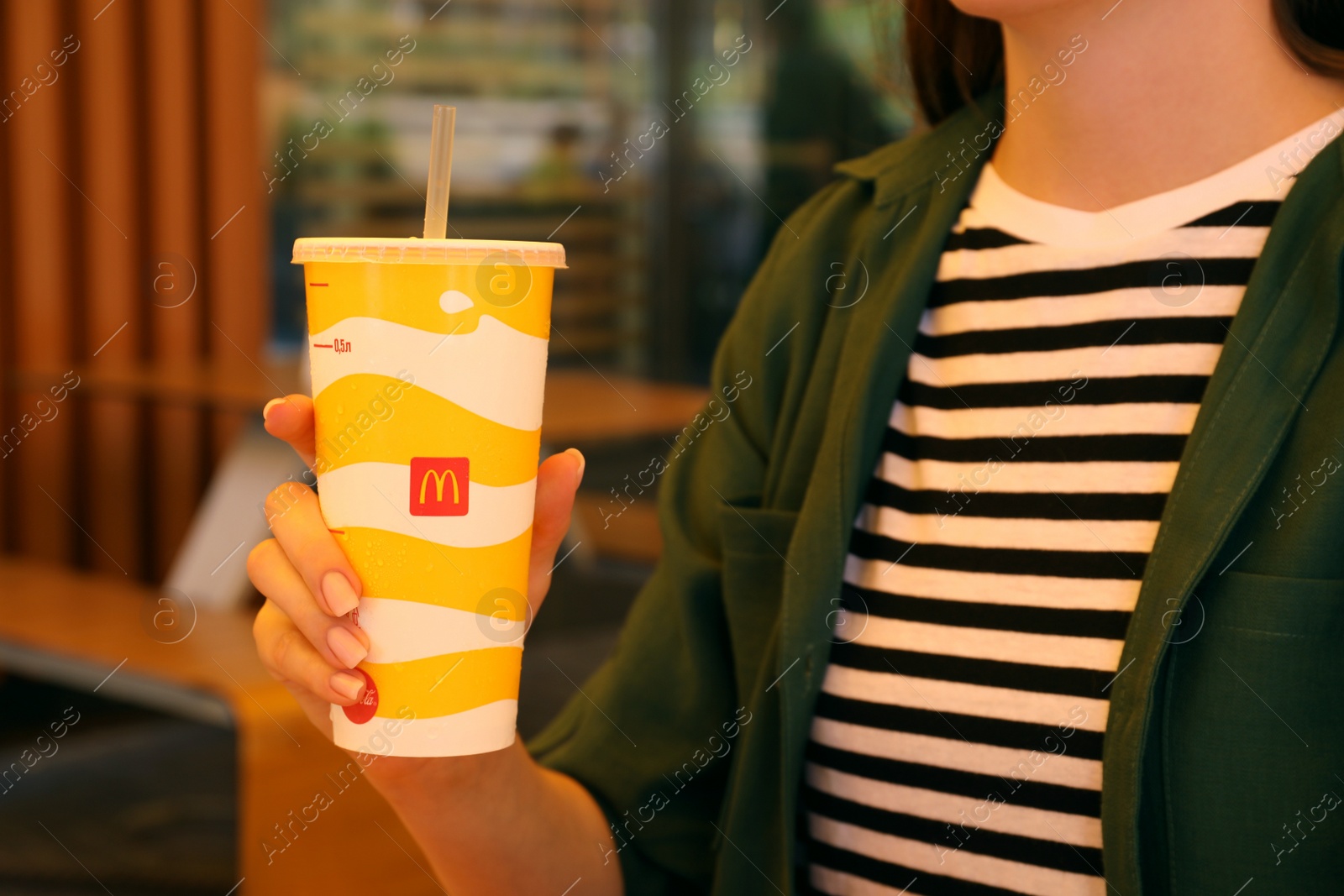 Photo of MYKOLAIV, UKRAINE - AUGUST 11, 2021: Woman with cold McDonald's drink in outdoor cafe, closeup