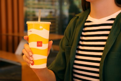 Photo of MYKOLAIV, UKRAINE - AUGUST 11, 2021: Woman with cold McDonald's drink in outdoor cafe, closeup