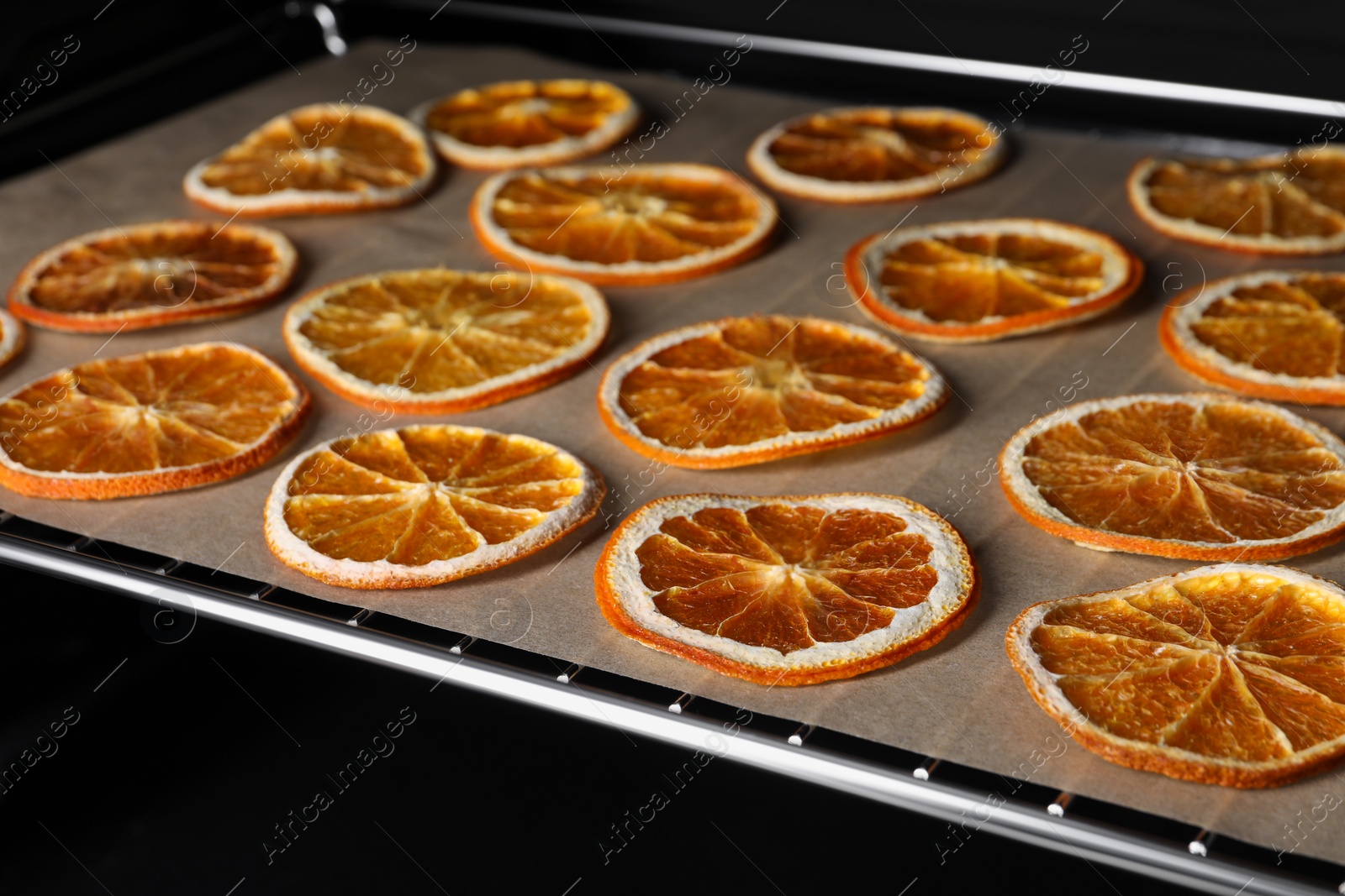 Photo of Dry orange slices on parchment paper, closeup